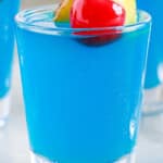 Blue Hawaiian Jello Shots in small shot glasses, garnished with fresh fruit.