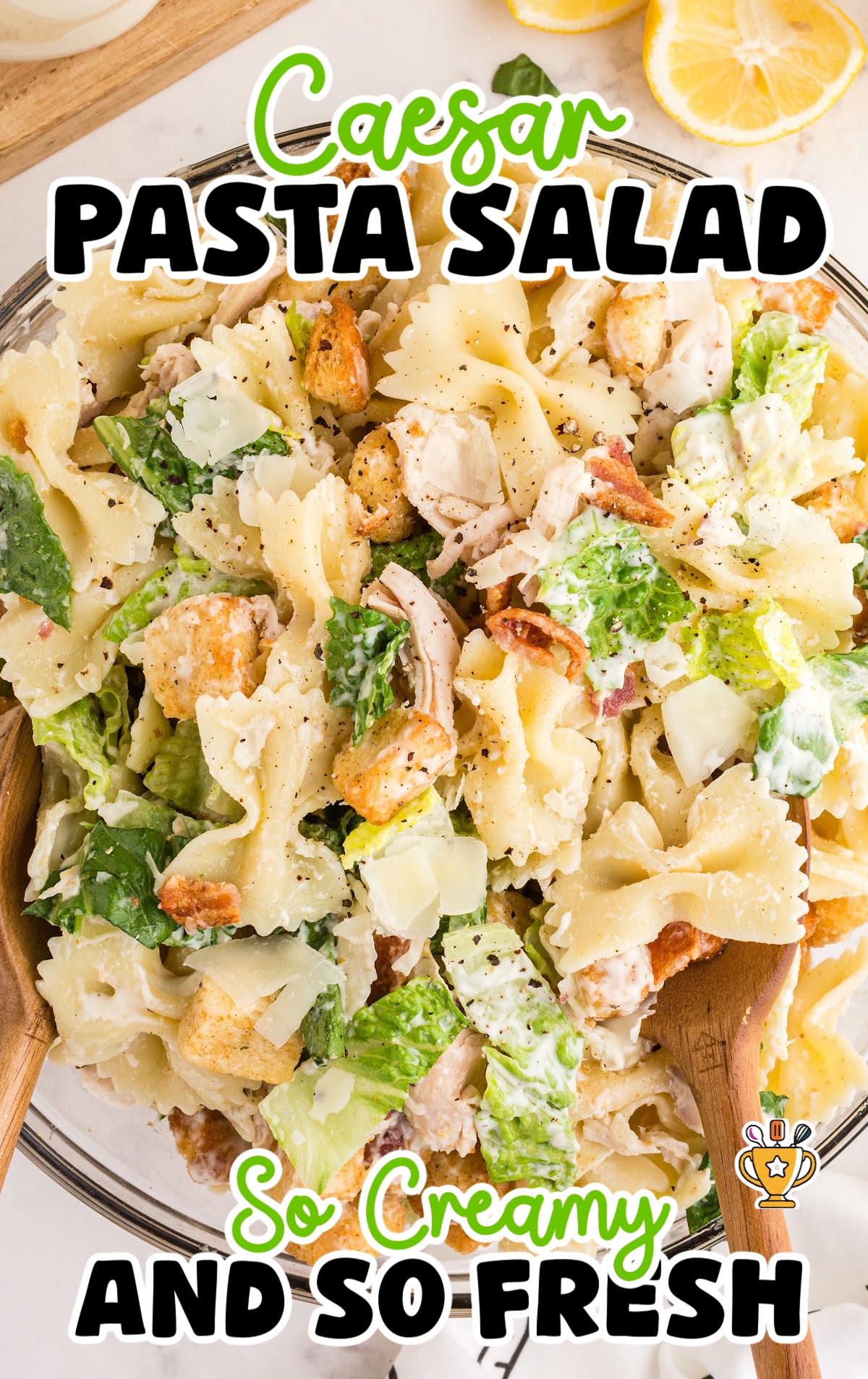 Top view of Caesar pasta salad featuring bowtie noodles, chopped romaine, shaved parmesan, bacon bits, and creamy dressing.