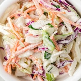 An overhead image of a bowl of finished coleslaw, showcasing the creamy, colorful mixture of veggies and herbs.