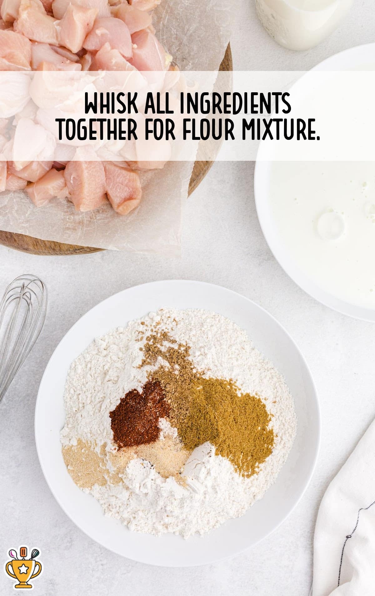 Plate with flour and spices ready for mixing, chopped raw chicken in the background.