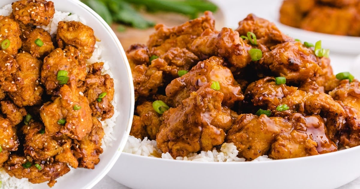 &ldquo;Two bowls filled with crispy honey chicken served over steamed white rice with sesame seeds and scallions.&rdquo;
