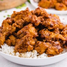 Bowl of golden fried honey chicken glazed with sauce and served over fluffy white rice.