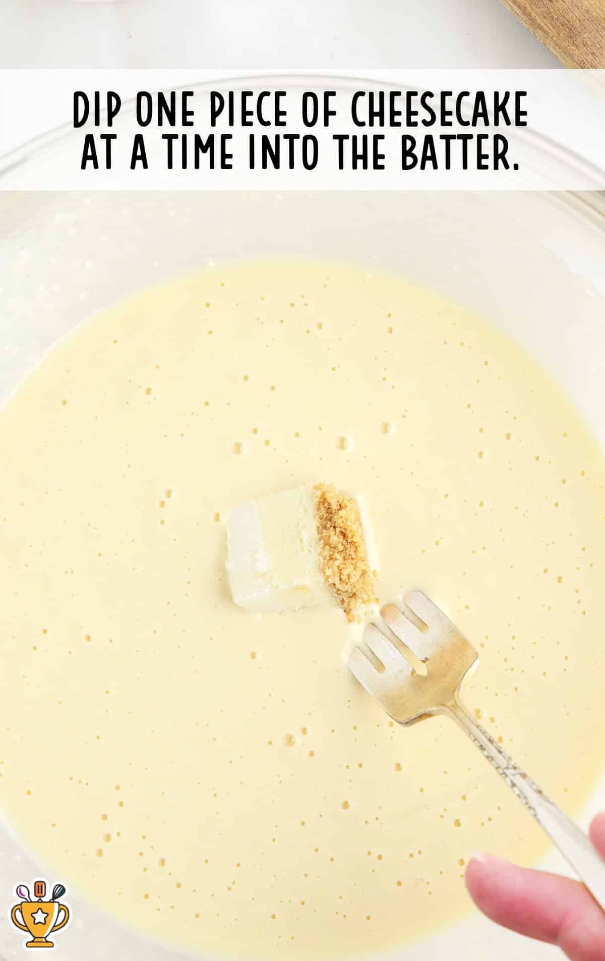 dipping a piece of cheese into the batter