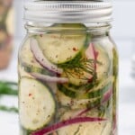 Mason jar of cucumber salad with overlay text reading "How to Make Easy Pickled Cucumber Salad – Marinated in Vinegar & Spices!"