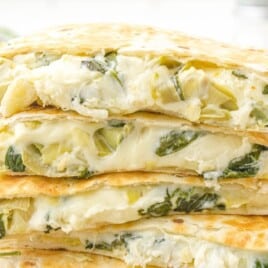 a stack of Spinach Artichoke Quesadilla pieces on a wooden board