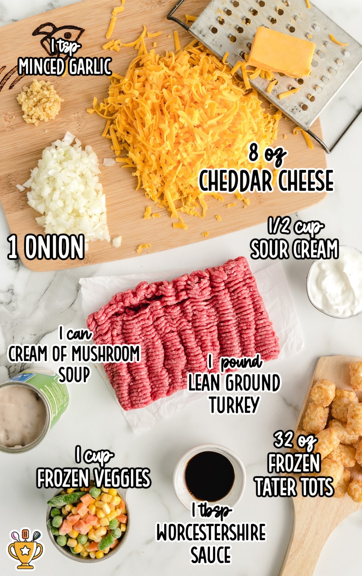 Overhead of labeled ingredients on white marble: ground turkey, cheese, soup, garlic, onion, Worcestershire sauce, sour cream, veggies, and tater tots.