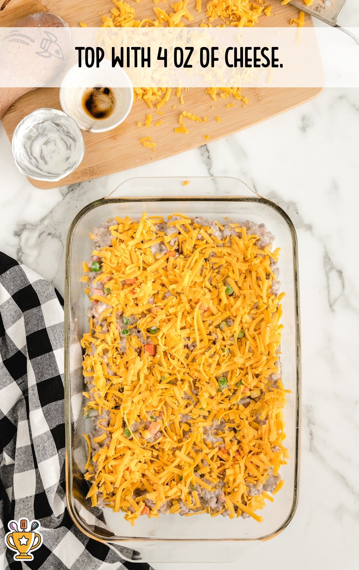 Shredded cheddar cheese spread generously over the beef and veggie mixture in the baking dish.