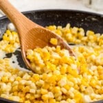 Honey Butter Skillet Corn in a skillet with a wooden spoon