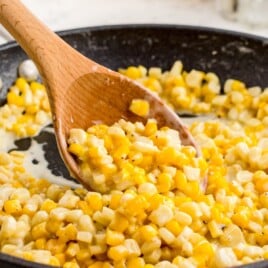 Honey Butter Skillet Corn in a skillet with a wooden spoon