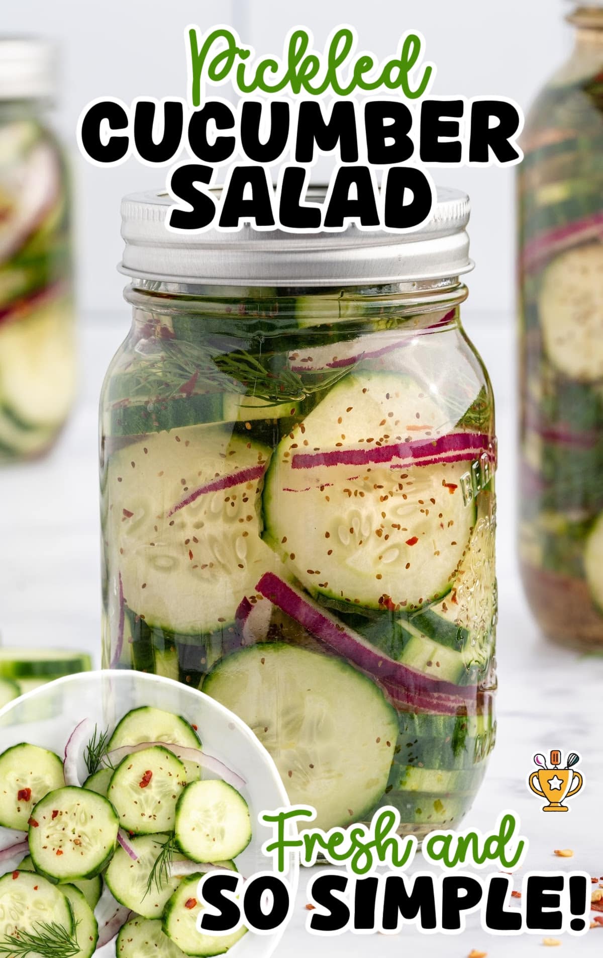 Close-up mason jar of pickled cucumber salad with red onions and dill against a white tile background