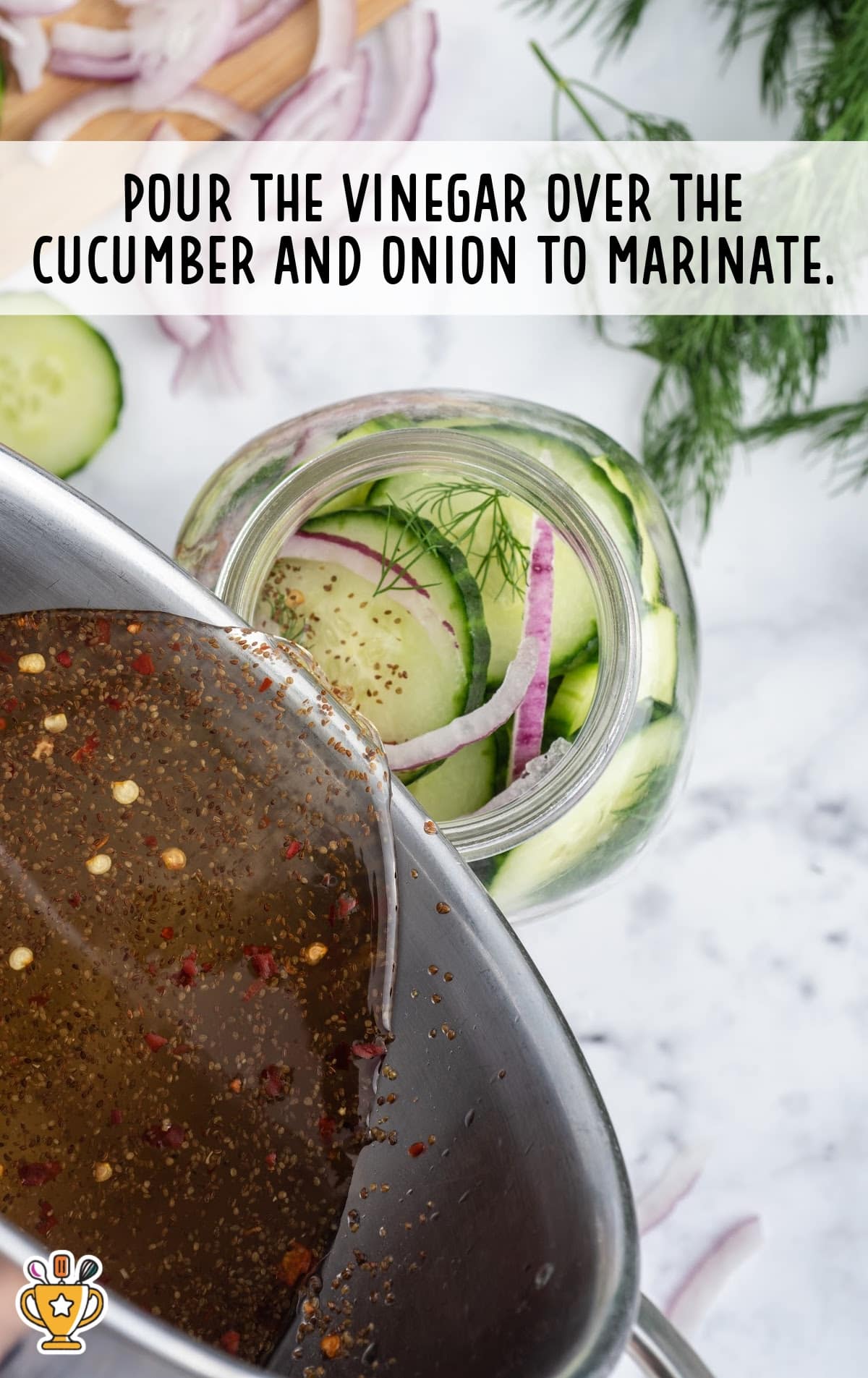Vinegar and spice mixture being poured over sliced cucumber, onion, and dill in a jar