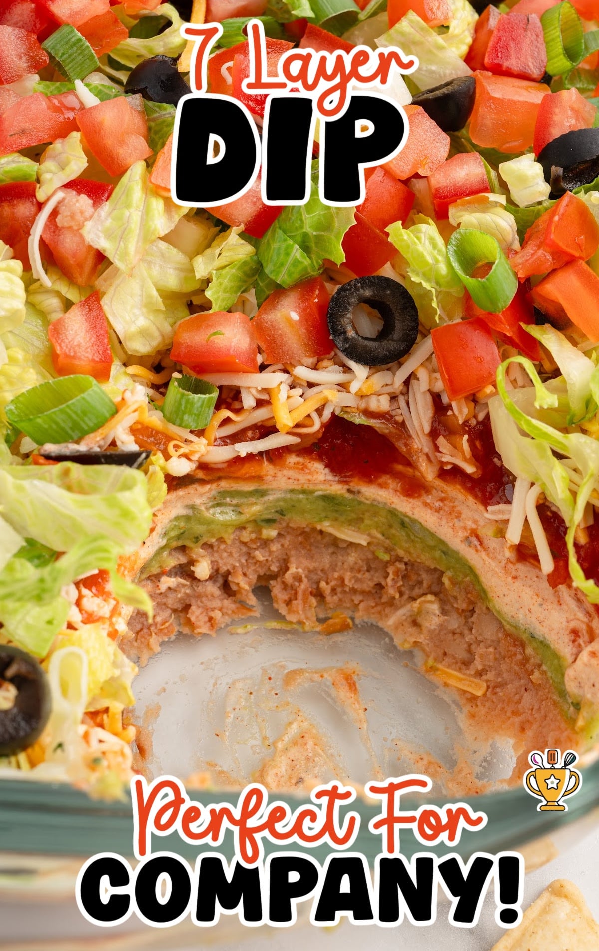Overhead view of 7 layer dip with a scoop taken out, revealing layers of beans, guacamole, sour cream, and salsa.