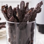 Glass filled with teriyaki beef jerky and an air fryer basket shown below with text reading “Yummiest Snack Ever!”