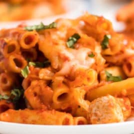 Side-by-side images showing a skillet of pasta mixed with tomato sauce and fresh herbs on the left and a plated serving of cheesy baked ziti with chicken on the right.