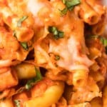 Tall graphic image with baked ziti topped with cheese and basil, labeled &ldquo;Baked Ziti with Chicken&rdquo; and &ldquo;hearty one pan meal!&rdquo; with a small skillet photo and arrow.