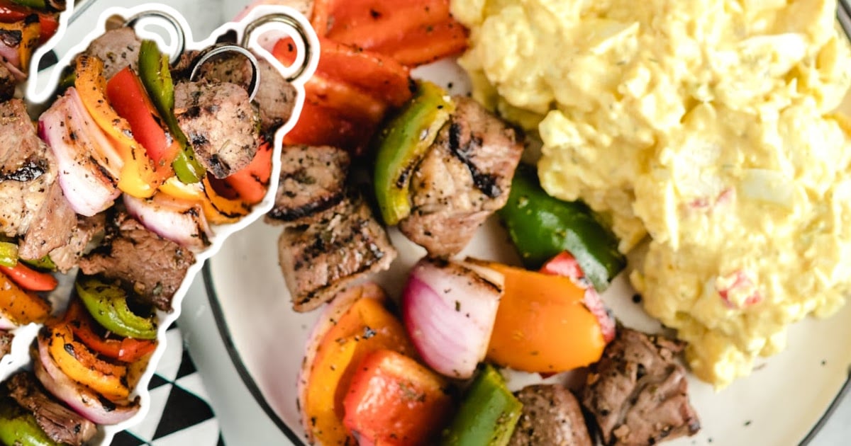 Plated meal of beef kabobs and potato salad, featuring vibrant grilled veggies and a close-up cutout of skewers.