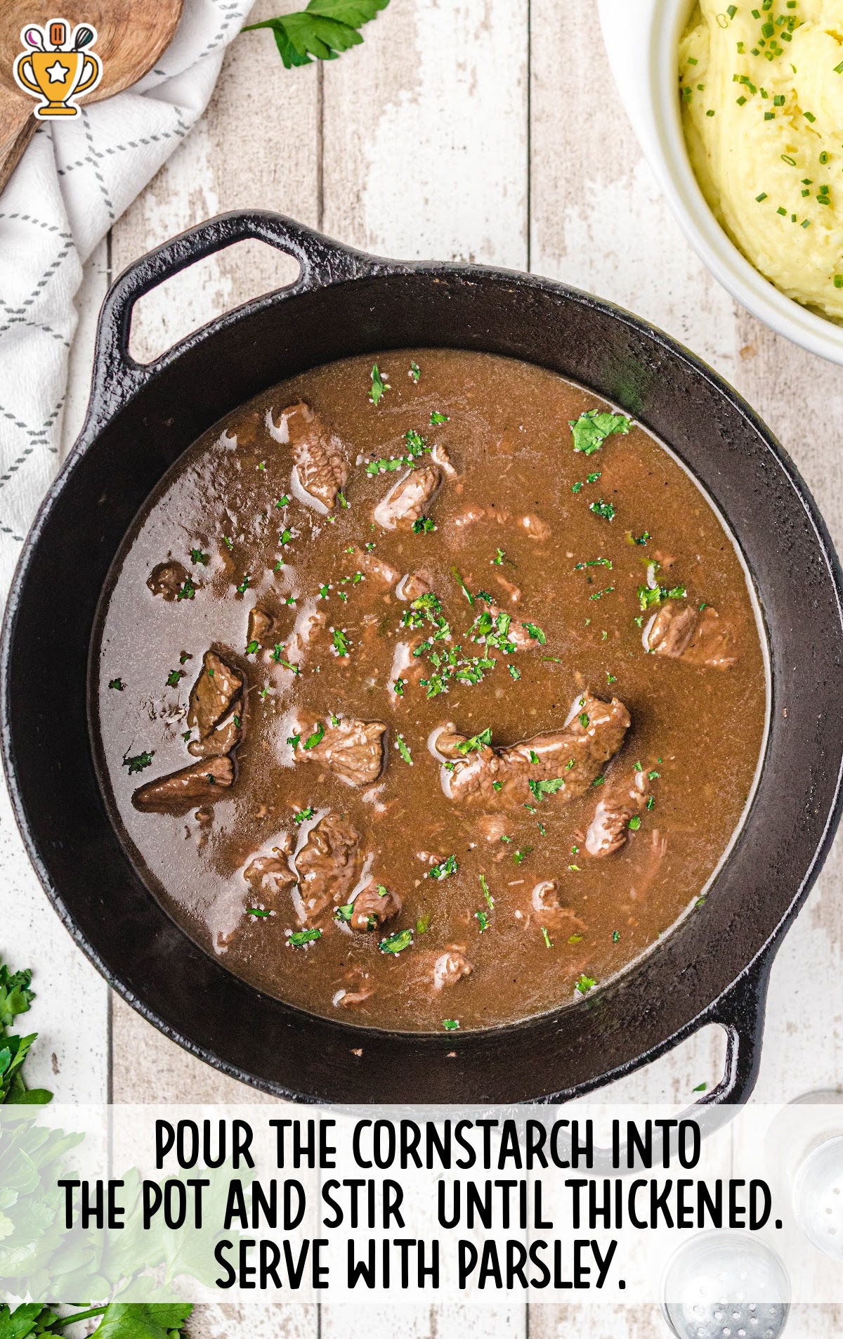 Thickened beef gravy with tender beef chunks simmering in a skillet, ready to serve with parsley on top.