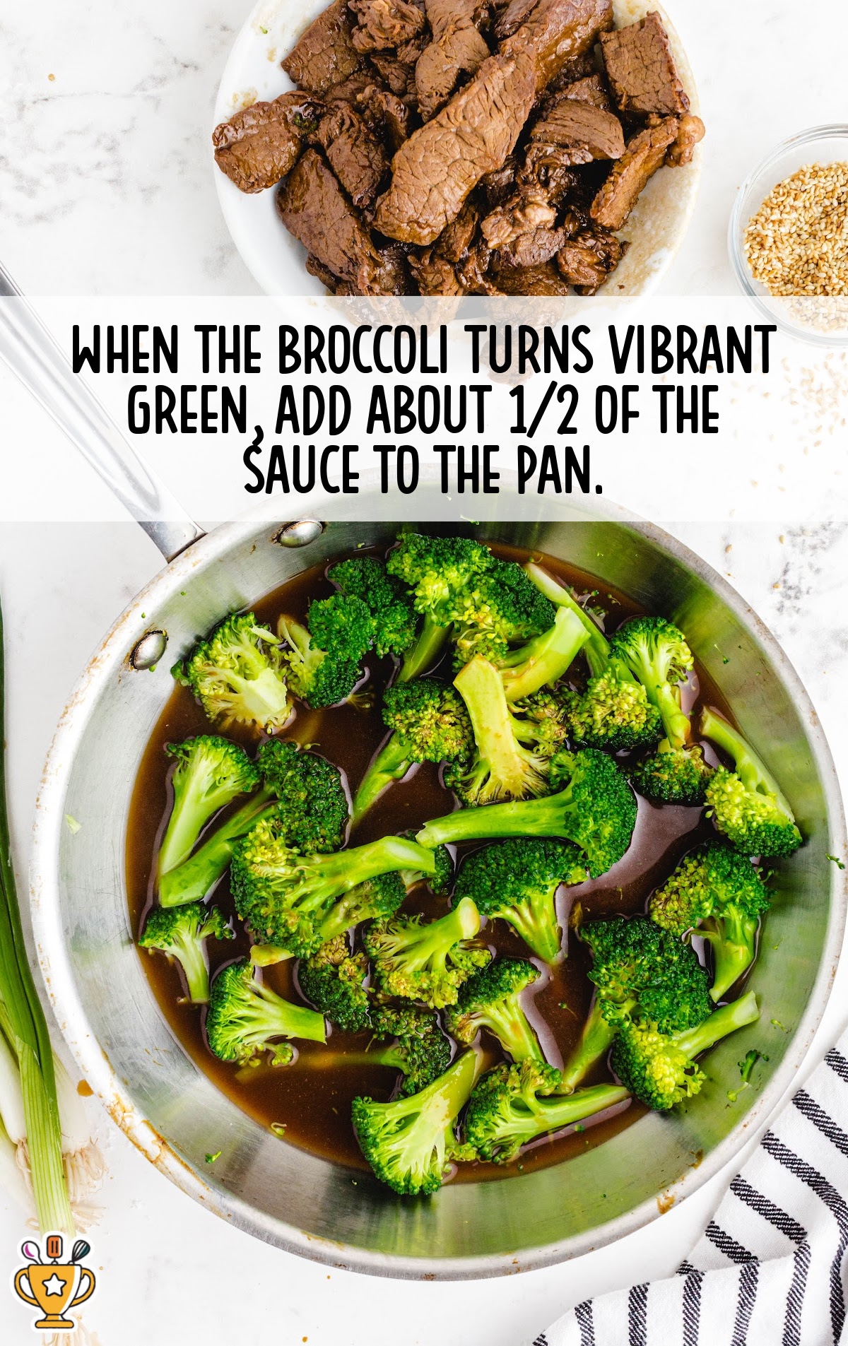 Broccoli florets cooking in sauce in a stainless steel pan with steak, sesame seeds, and sauce ingredients nearby.