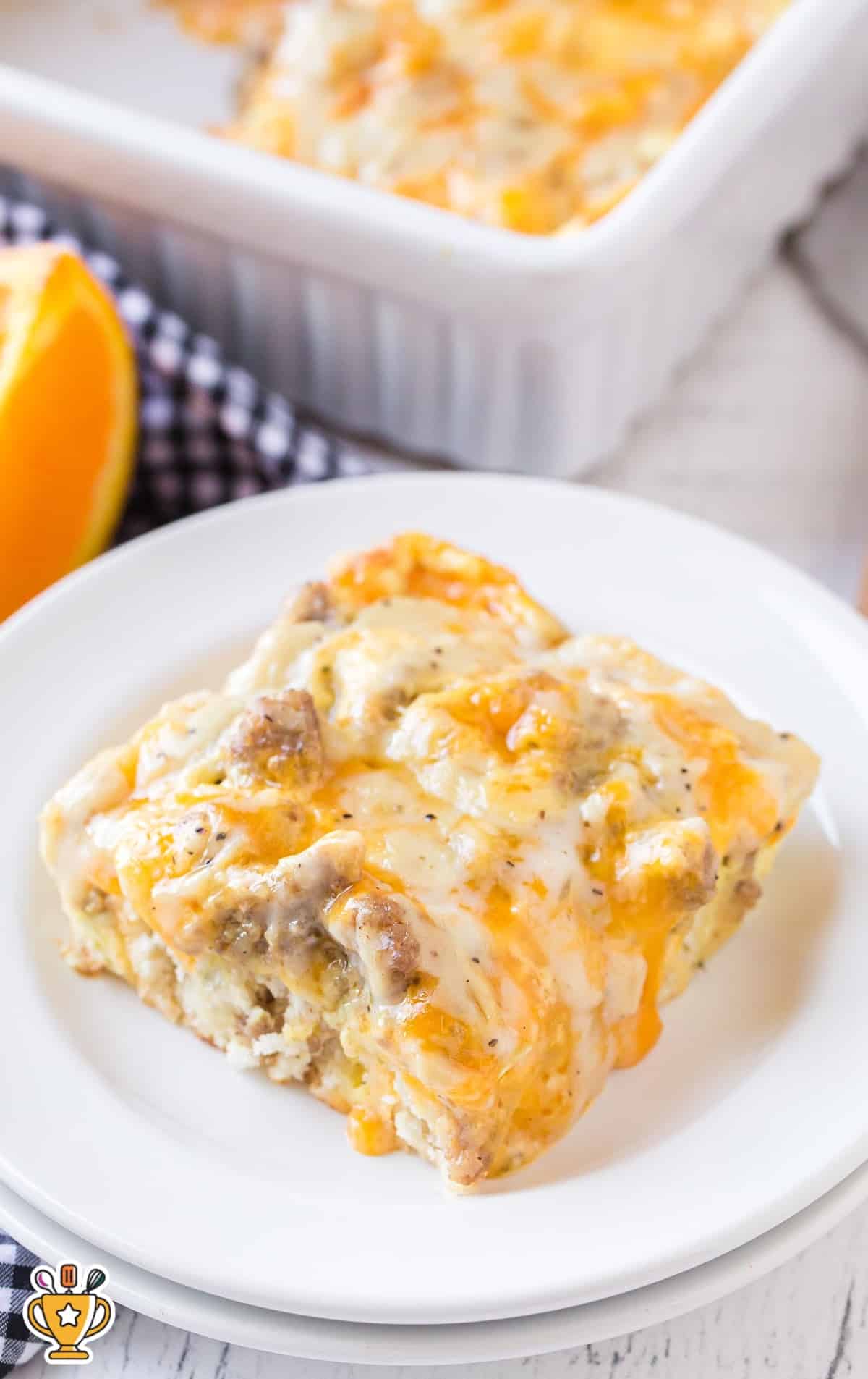 A single serving of breakfast casserole on a white plate with melted cheese, sausage, and fluffy biscuit layers, ready to eat.