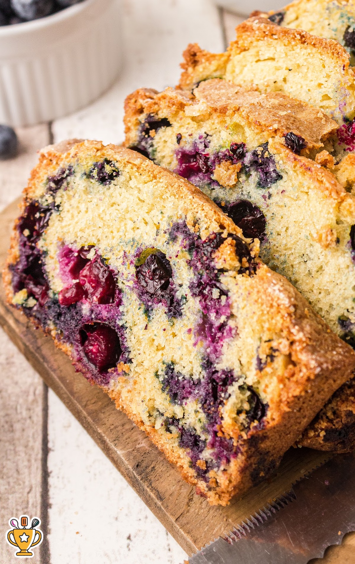 Top view of blueberry bread slice on a plate next to a bowl of flour-dusted blueberries, ready for baking.