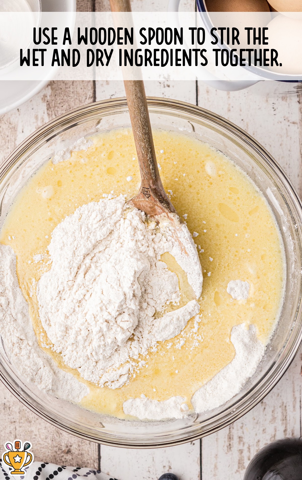 Flour added to wet mixture in a bowl with a wooden spoon, with instruction to stir ingredients together