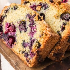 Close-up shot of golden blueberry bread slices on a cutting board, bursting with juicy blueberries and a crunchy crust.