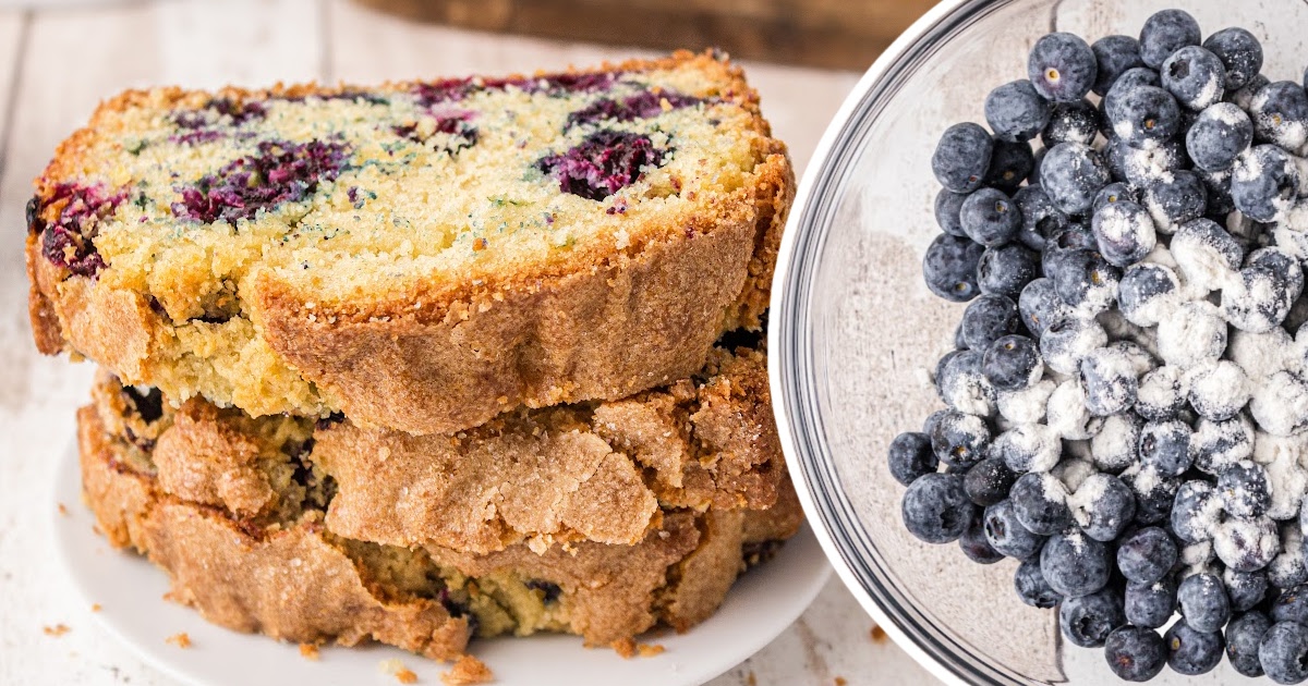 Whole blueberry loaf with a moist interior and golden crust, partially sliced to show juicy berries throughout.