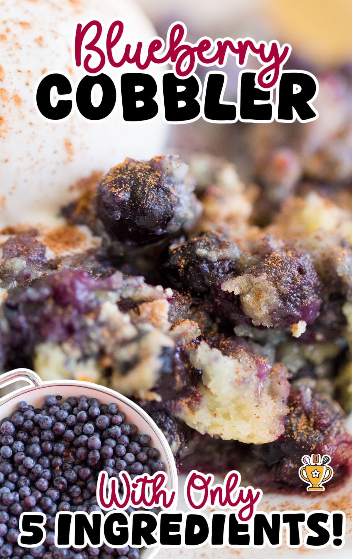 A large serving spoon lifting a thick, gooey portion of blueberry cobbler from a baked dish.
