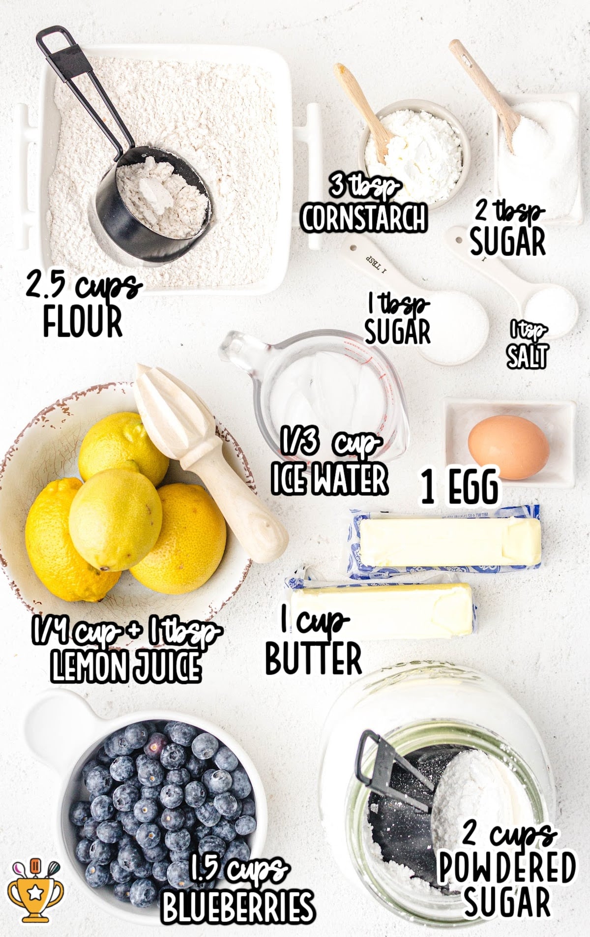 Top view of ingredients needed for blueberry hand pies, including flour, lemons, blueberries, butter, sugar, and cornstarch.