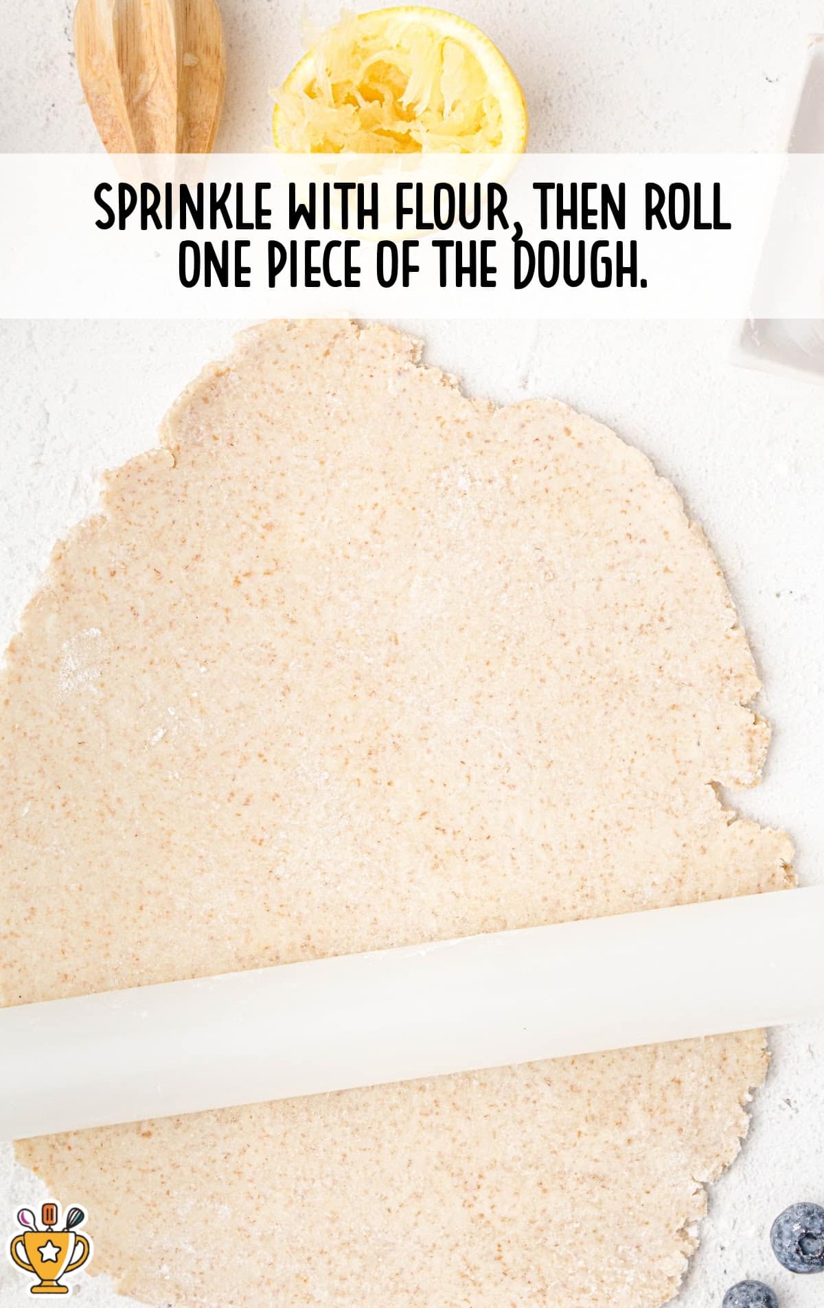 Dough rolled out into a thin sheet with a rolling pin, sprinkled lightly with flour on a white surface.