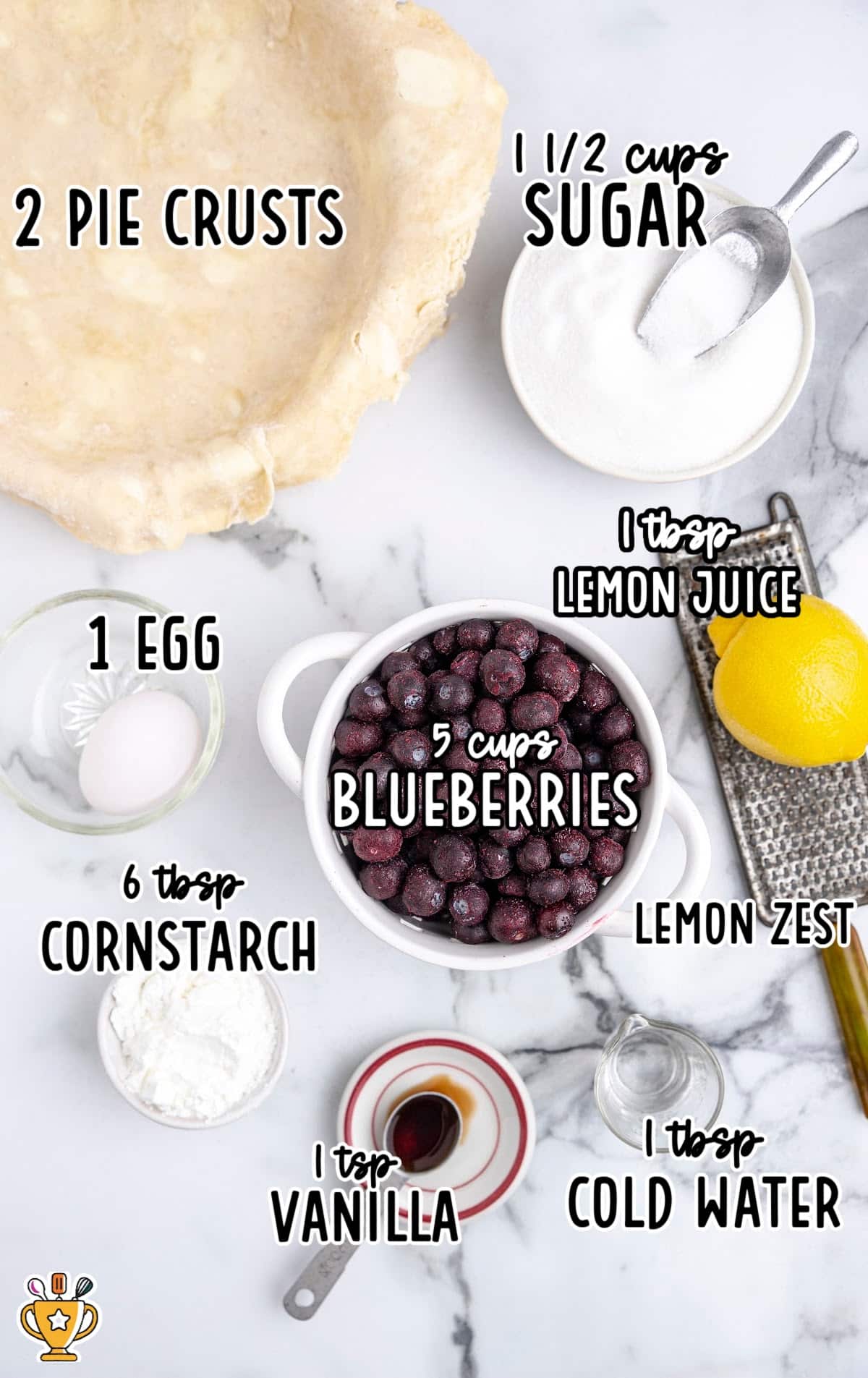 Flat lay of ingredients for blueberry pie, including pie crusts, sugar, frozen blueberries, cornstarch, vanilla, lemon, and egg.
