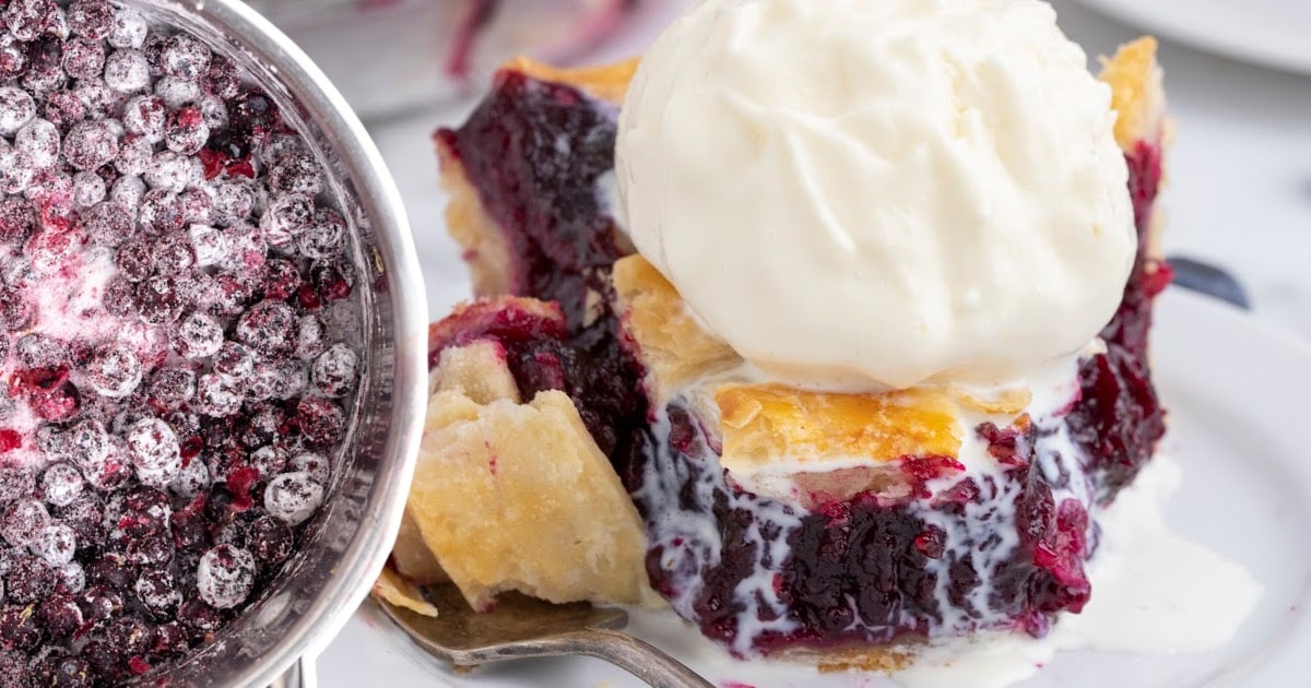 Slice of blueberry pie with vanilla ice cream, side-by-side with a pot of sugar-coated frozen blueberries.