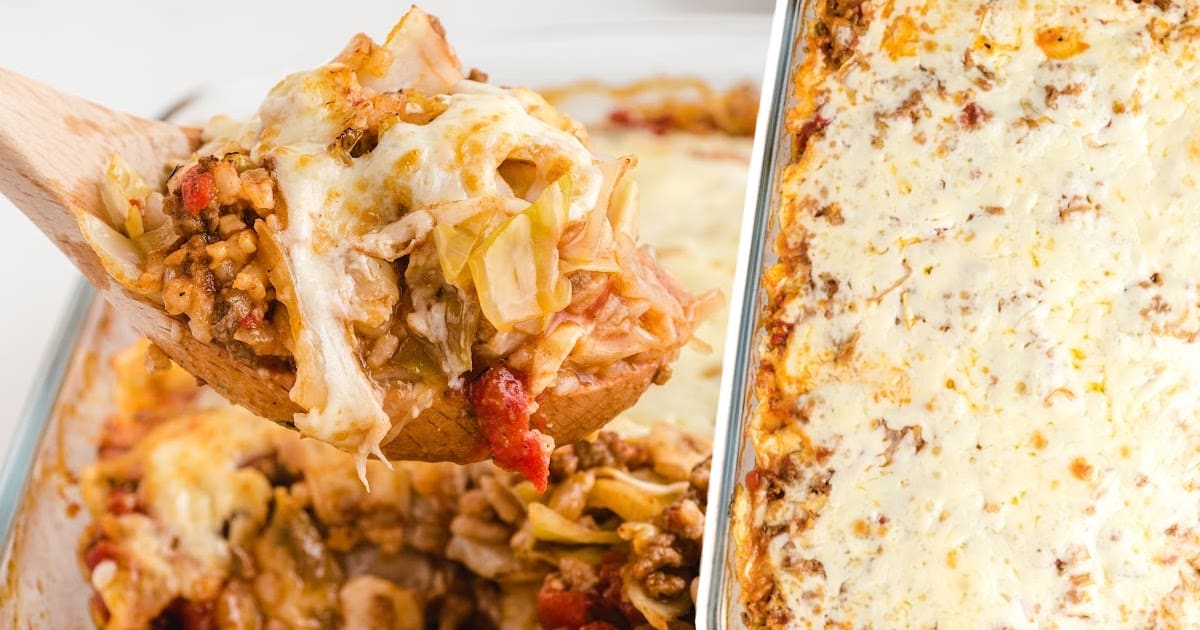 Spoonful of cheesy cabbage roll casserole lifted above a dish, with a view of the full casserole topped with melted cheese.