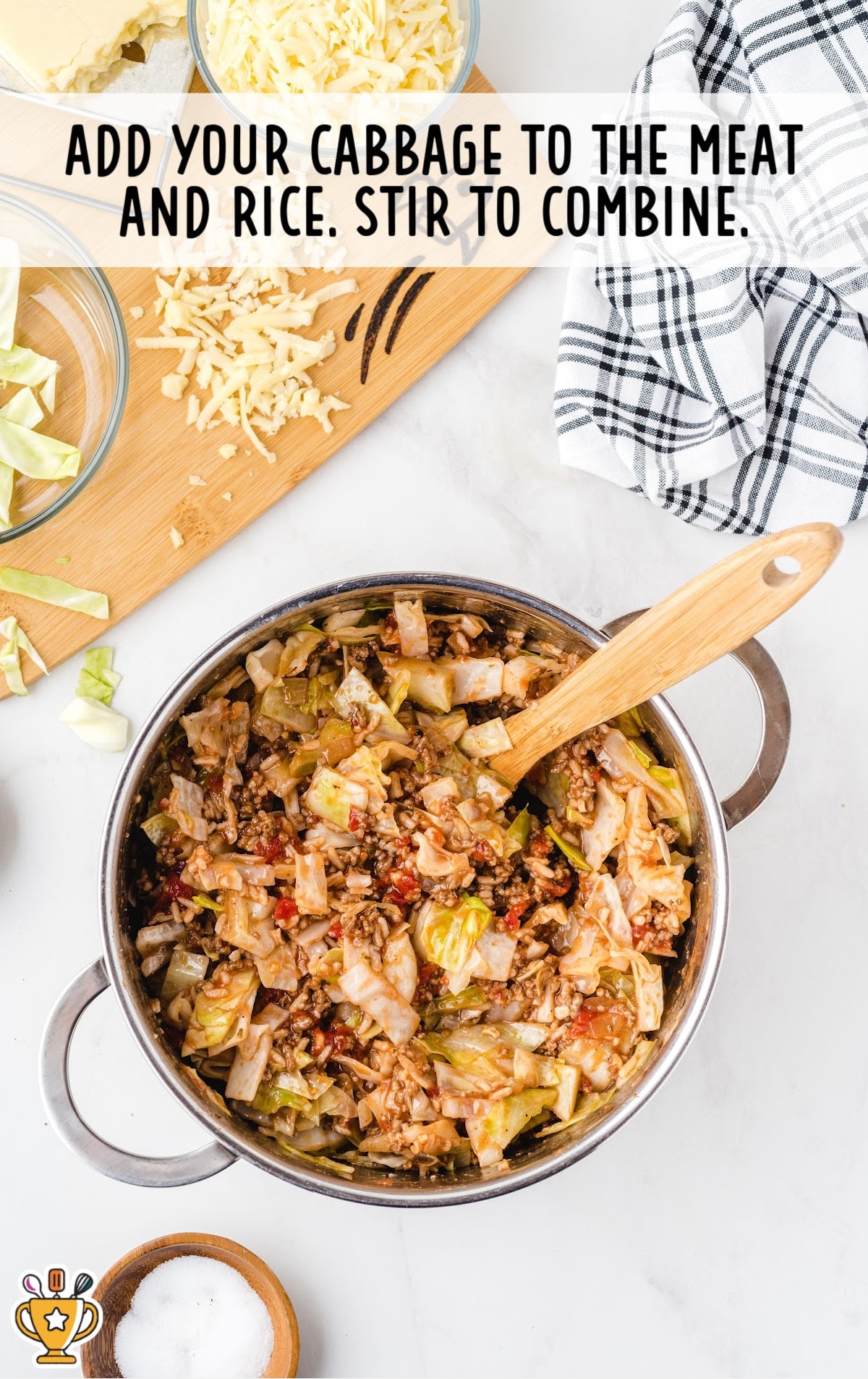Cabbage stirred into the beef and rice mixture in a large pot with a wooden spoon, forming the full casserole filling.