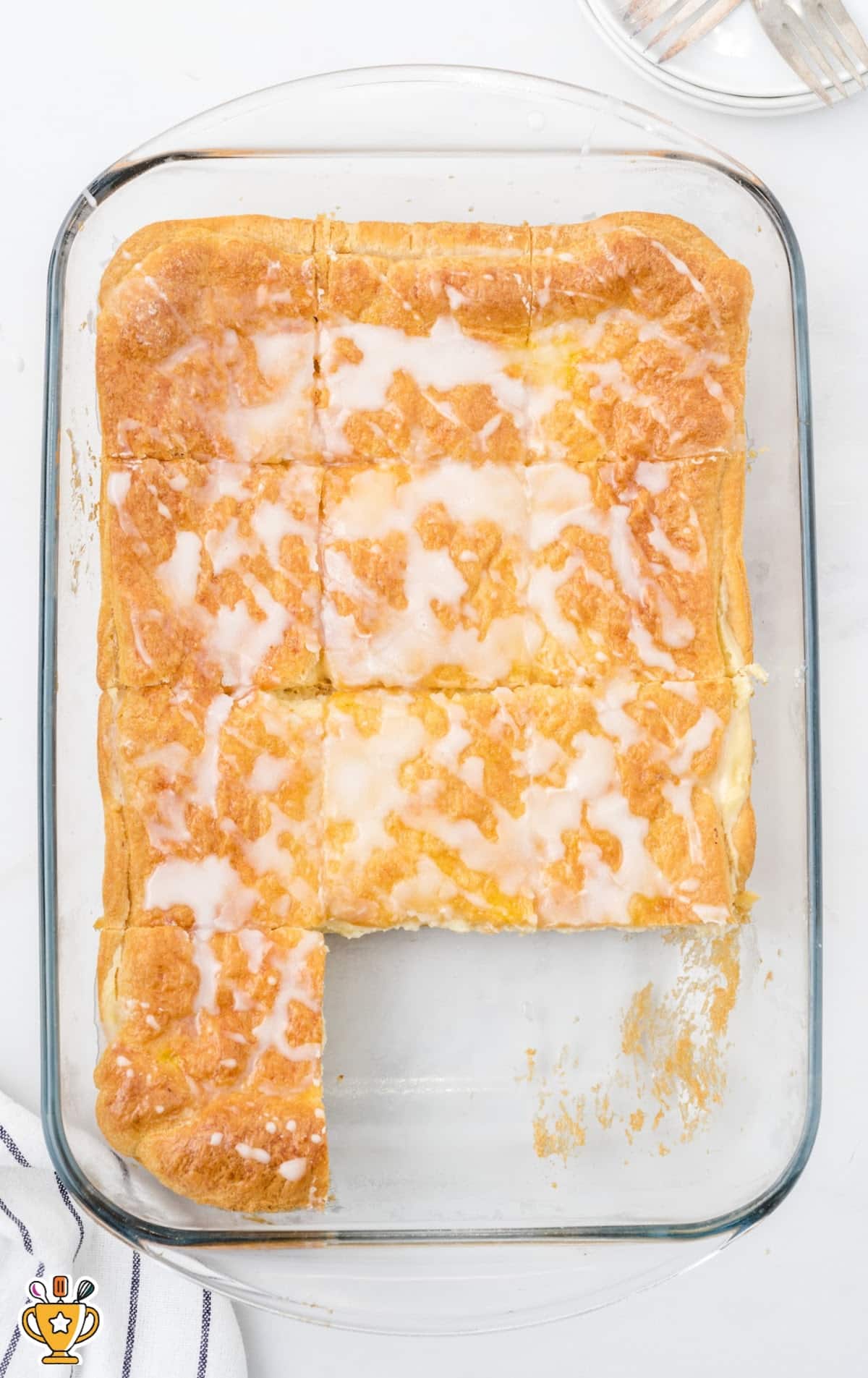 Single cheese danish square on a white plate with a fork beside it and glossy glaze on top.