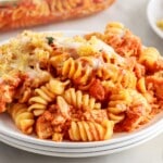 Hearty serving of chicken parmesan casserole with rotini, marinara sauce, and melted cheese, stacked on a white plate.