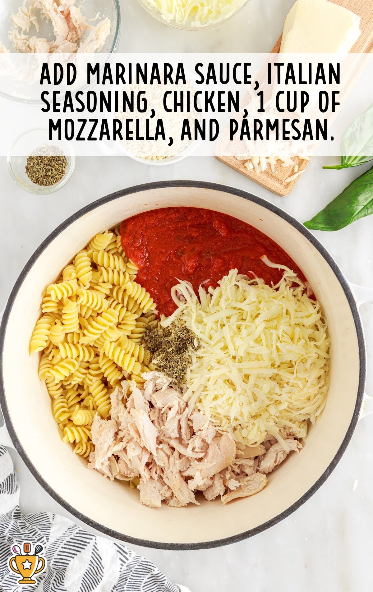 Overhead view of a pot filled with uncooked pasta, marinara, Italian seasoning, shredded mozzarella, chicken, and parmesan.