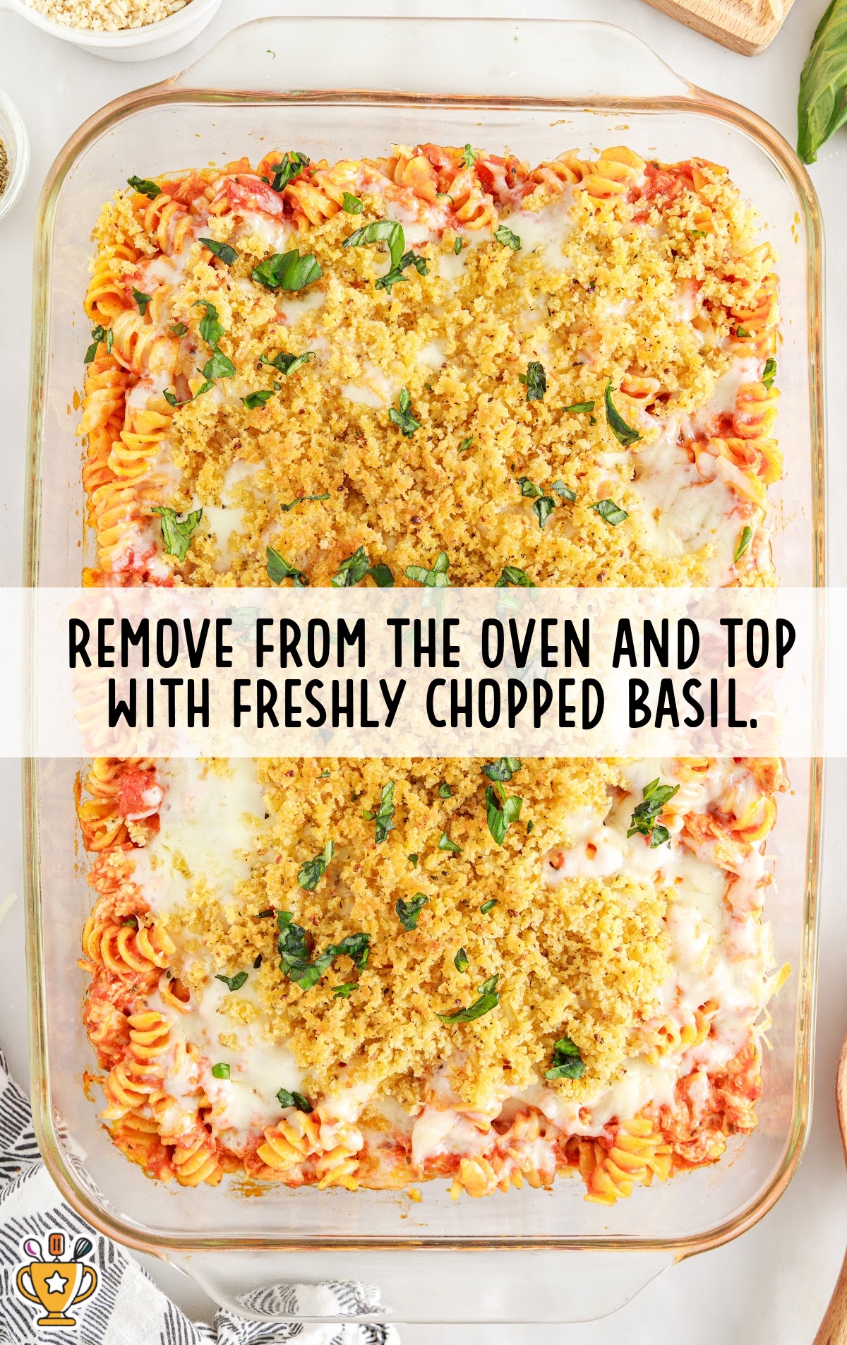 Finished casserole topped with freshly chopped basil and melted cheese under a golden breadcrumb crust.