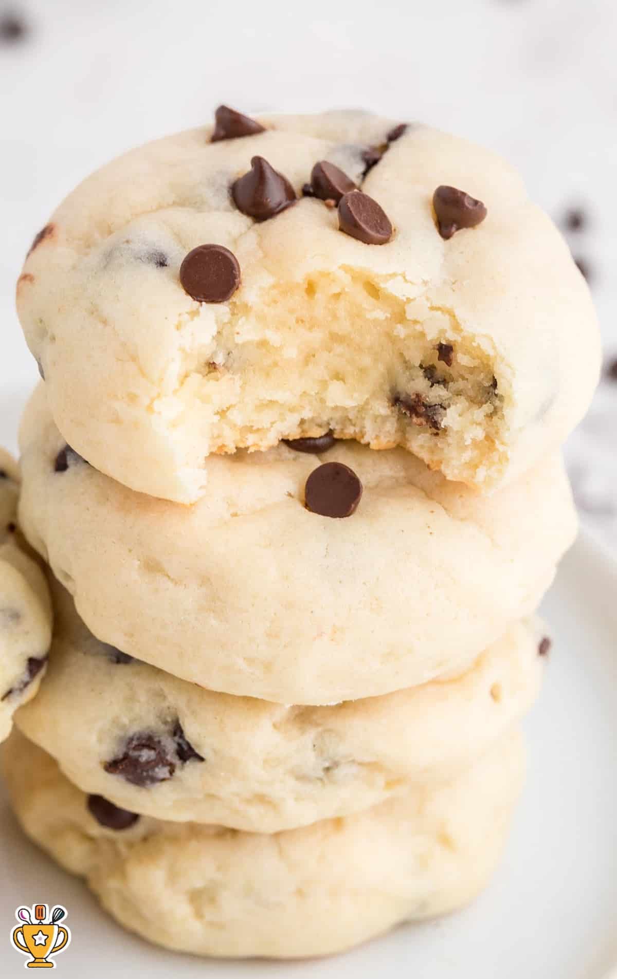 Close-up of a chocolate chip cheesecake cookie with a bite taken out, revealing soft cheesecake interior.