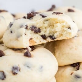 Chocolate chip cheesecake cookies with one broken open, showing the creamy inside and scattered chocolate chips.