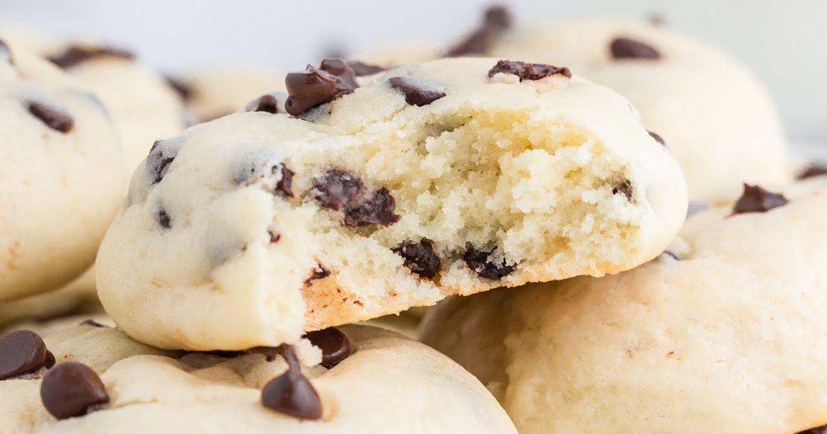 Stack of golden chocolate chip cheesecake cookies topped with mini chocolate chips on a white plate.