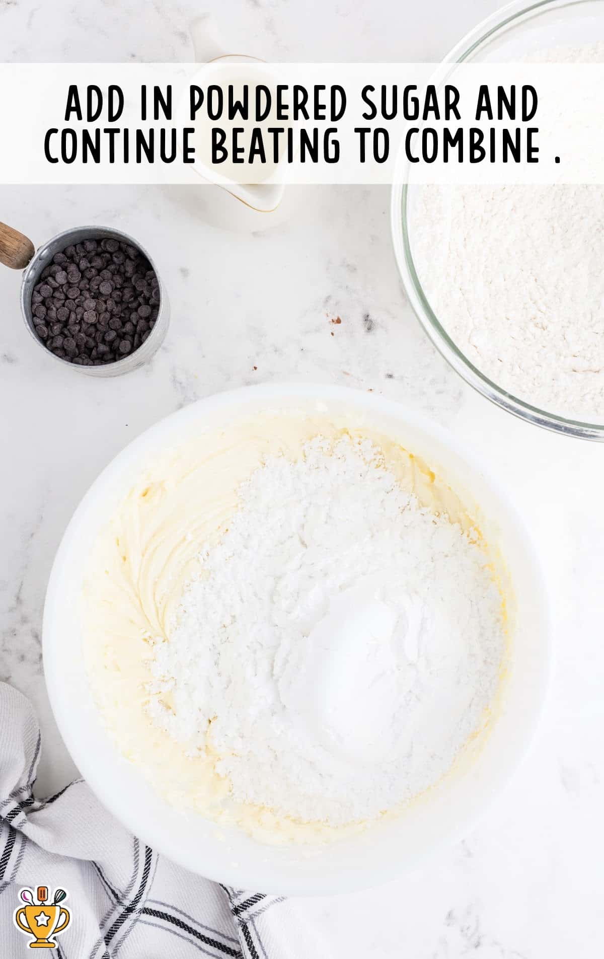 Powdered sugar added to the bowl of creamed butter and cream cheese mixture, ready to be mixed.