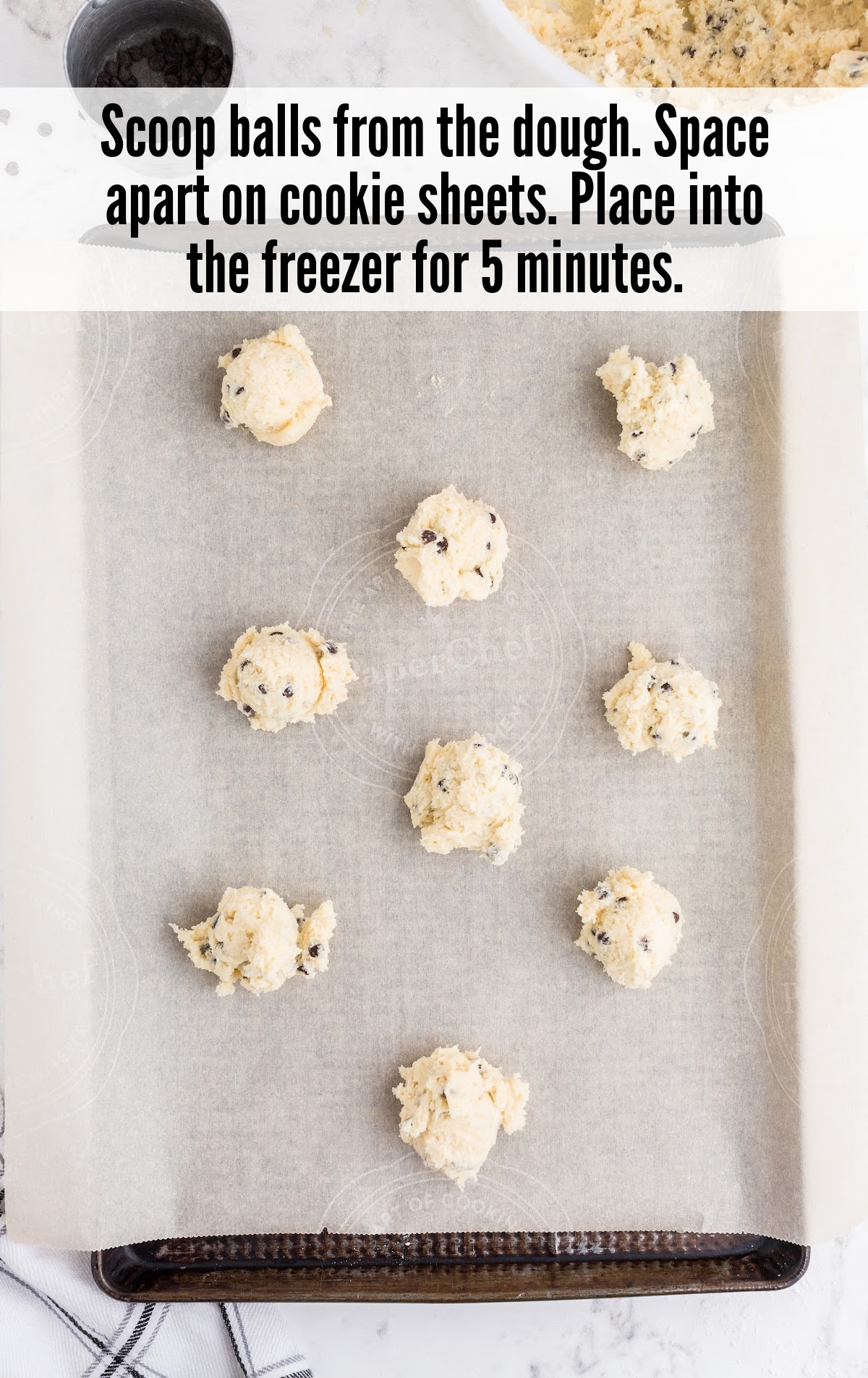 Scooped cookie dough balls spaced apart on a parchment-lined baking sheet, ready for freezing.