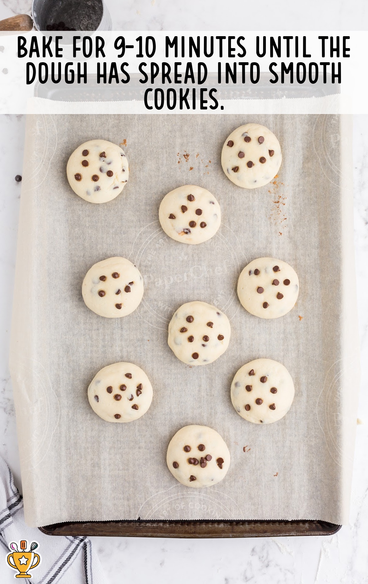 Freshly baked chocolate chip cheesecake cookies cooling on a parchment-lined baking sheet.