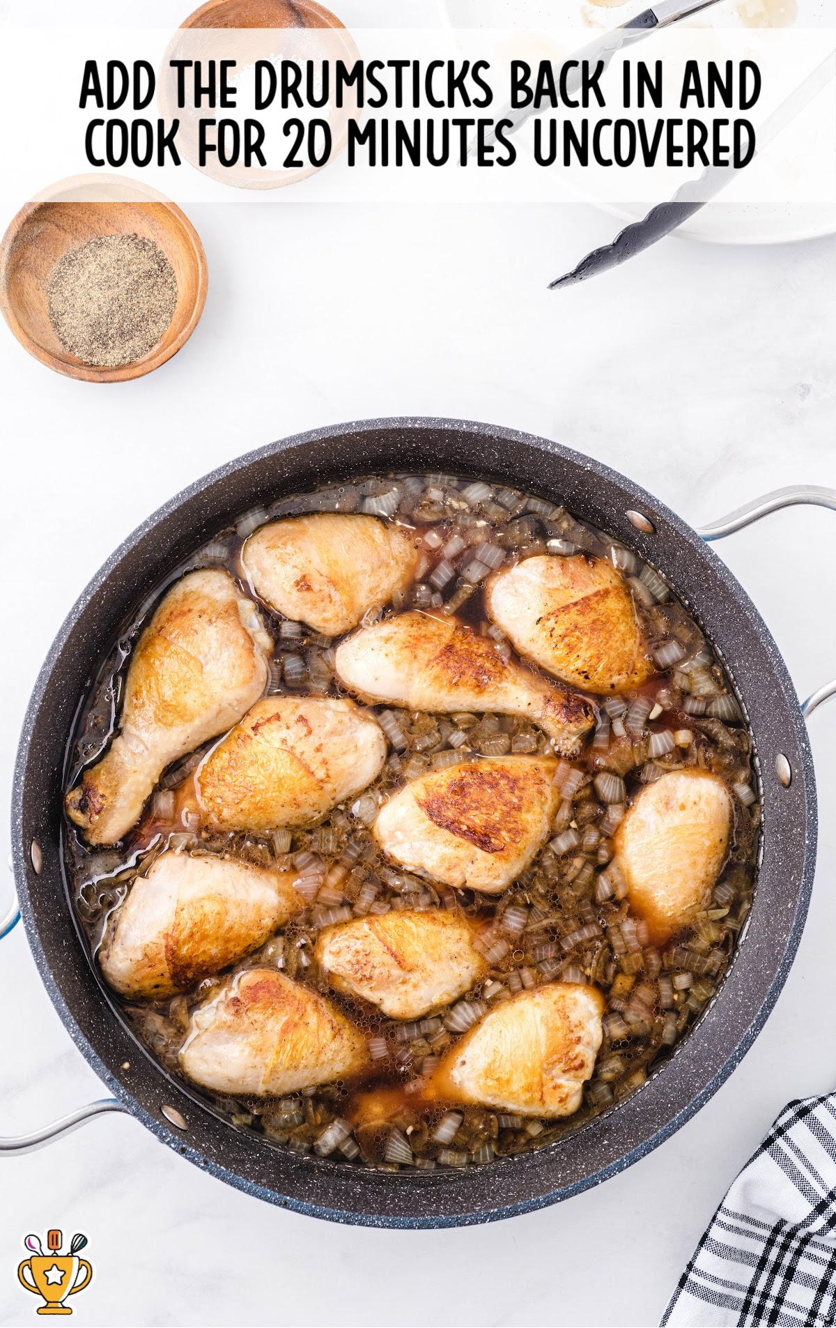 Top-down view of browned drumsticks placed back into the sauce mixture in the pan. Text says, “Add the drumsticks back in and cook for 20 minutes uncovered.”