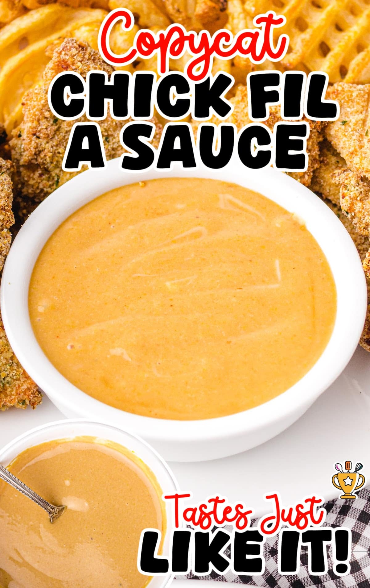 Bowl of creamy copycat Chick-fil-A sauce surrounded by crispy chicken tenders and waffle fries on a white plate.
