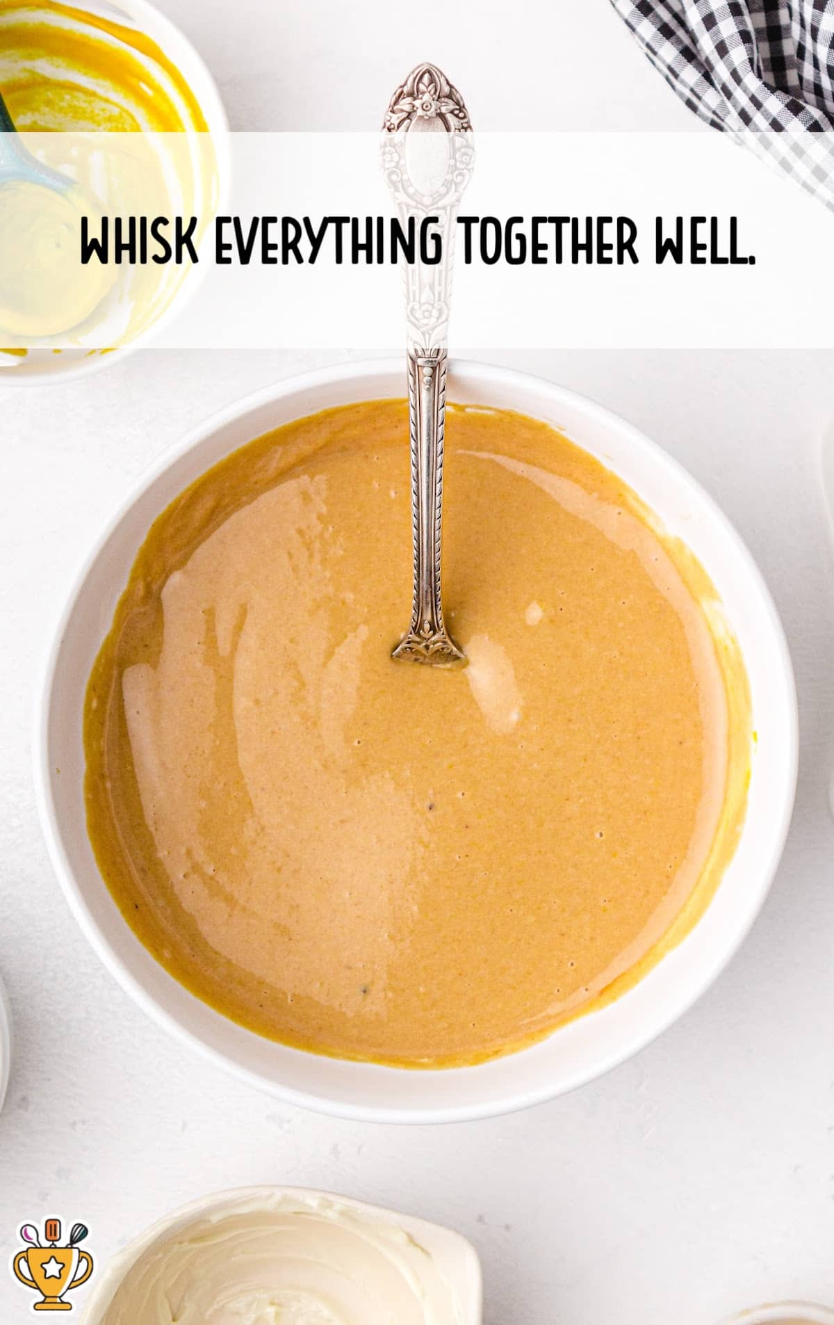 Overhead view of creamy copycat Chick-fil-A sauce whisked together smoothly in a bowl with a spoon standing in the middle.