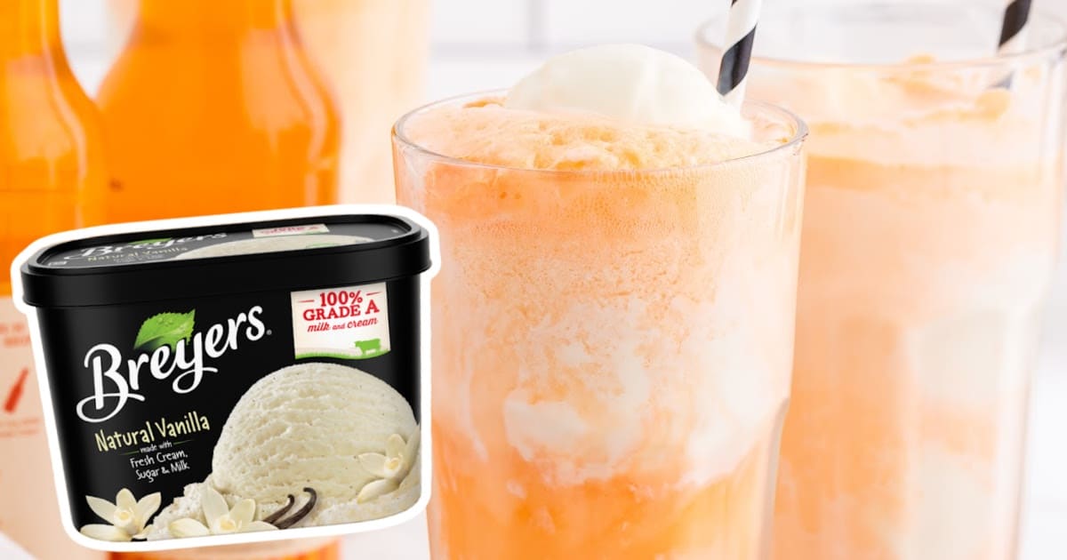 Tall glass filled with a creamy orange and vanilla cocktail float, topped with a scoop of vanilla ice cream and striped straw
