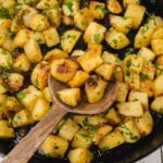 Crispy golden fried potatoes served in a black skillet with a wooden spoon, highlighted as a recipe card featuring the final dish.