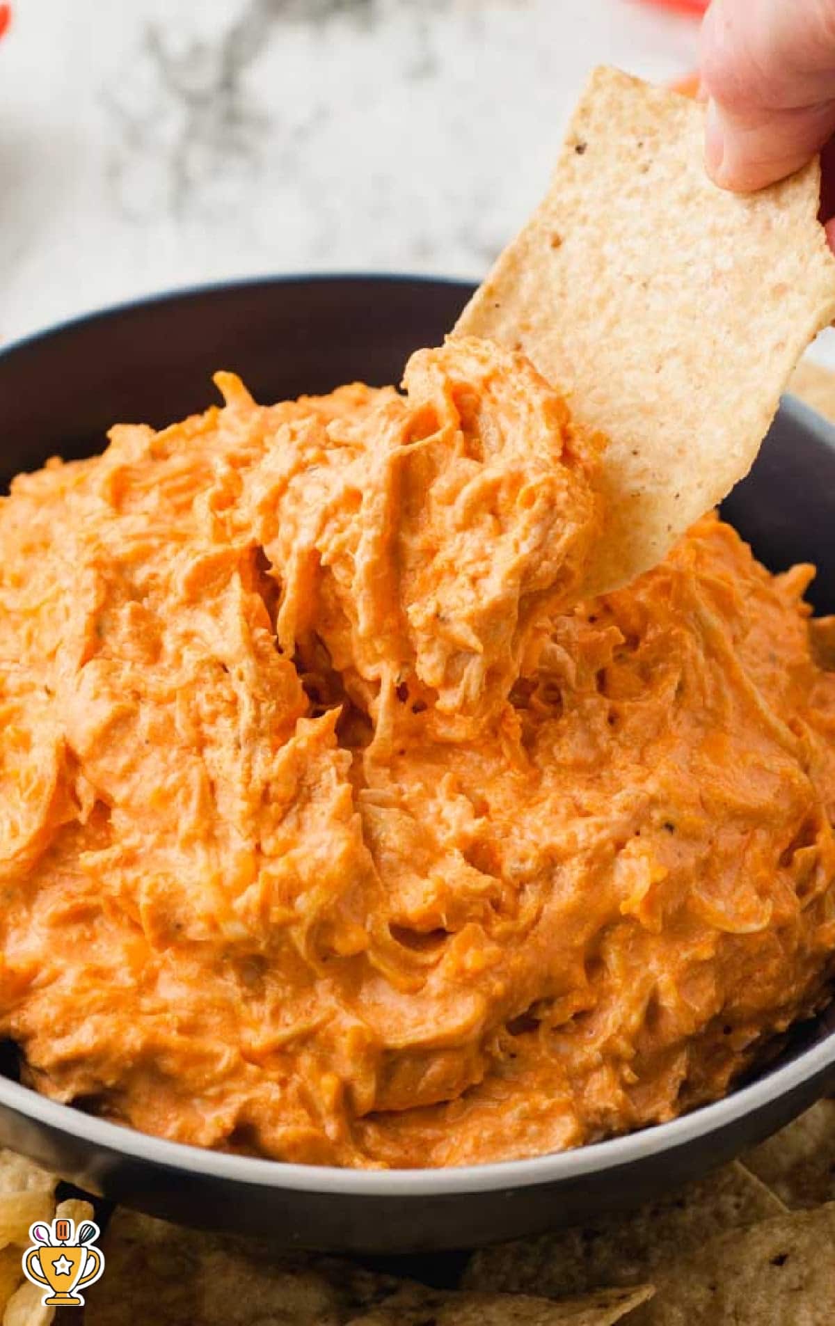Plate of crockpot buffalo chicken dip served with tortilla chips and vegetables, with a bold title overlay.